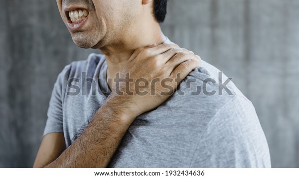 Close up young asian man suffering from\
shoulder pain at home, Ache in human\
body