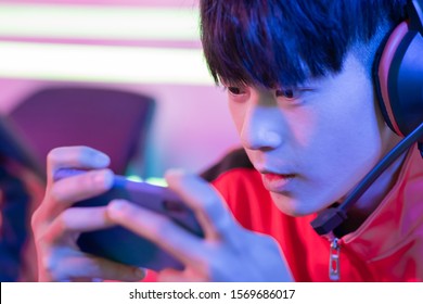 Close Up Of Young Asian Teenage Cyber Sport Gamer Play Mobile Game By Smartphone On ESport Tournament