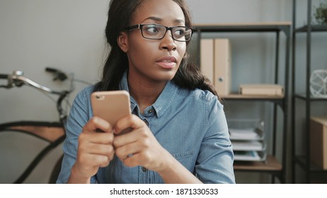 Close Up Of Young Beautiful African American Girl Sitting In Office And Writing Message That She Will Go Home From Work Earlier.