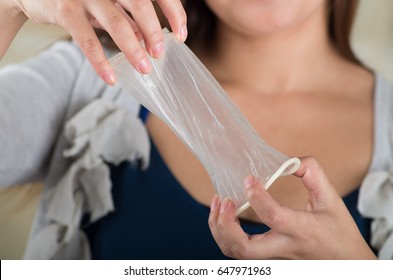 Close up of a young beautiful girl holding an open female condom, safe sex concept. Protection against AIDS and birth control