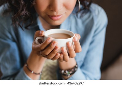 熱いコーヒーや紅茶をミルクで持つ若い美しい女性の手の接写