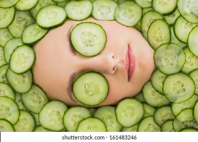 Close up of a young beautiful woman with facial mask of cucumber slices on her face at spa salon - Powered by Shutterstock