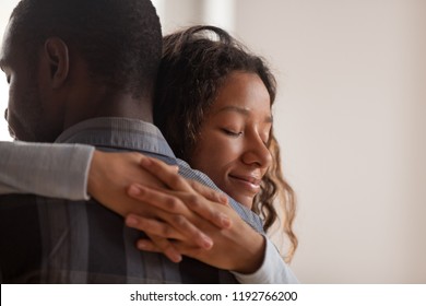 Close up young black american wife embracing husband. Portrait of woman with closed eyes, man rear view. Attractive affectionate couple in love, romantic relationship support and gratefulness concept
