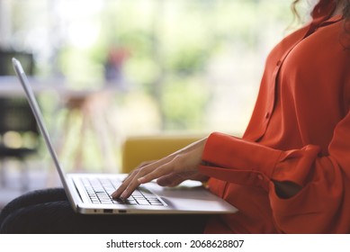 Close Up Young Black Woman Wearing Orange Shirt Using Laptop For Shopping Online, Leaning Online, And Video Call On Sofa At Home. Business Woman Work From Home In Spreading Of Coronavirus Covid-19.