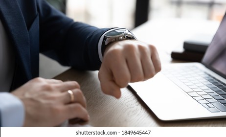 Close up young businessman in formal wear checking time on stylish wristwatch, waiting for important online video call meeting, planning workday, feels hurry in office, time management concept. - Powered by Shutterstock