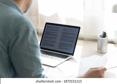 Close Up Young Businessman Working On Research Project, Checking Documents, Holding Paper Sheet, Looking At Laptop Screen, Student Writing Diploma, Essay, Sitting At Work Desk, Home Office