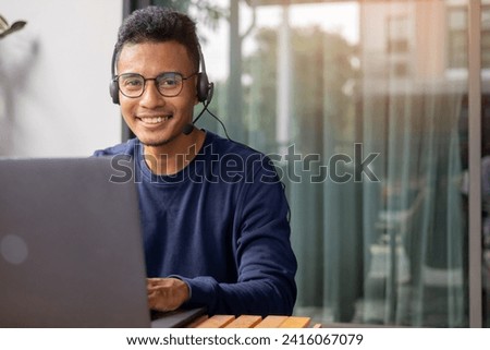 close up young call center indian man wear headset and smiling while working in office with service-mind for telemarketing and helpdesk agent  concept