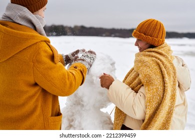 Close Up Of Young Couple Building Snowman Together While Enjoying Winter Fun Outdoors