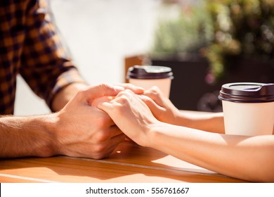 Close Up Of Young Couple Holding Each Other Hands In Cafe