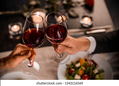 Close up of young couple toasting with glasses of red wine at restaurant - Powered by Shutterstock