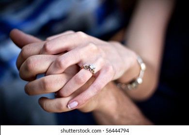 Close up of a young couples hands and diamond engagement ring with platinum and gold accents. Shallow depth of field.