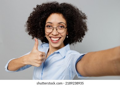 Close Up Young Employee Business Corporate Lawyer Woman Of African American Ethnicity In Formal Shirt Work In Office Doing Selfie Shot Pov On Mobile Phone Show Thumb Up Isolated On Grey Background.