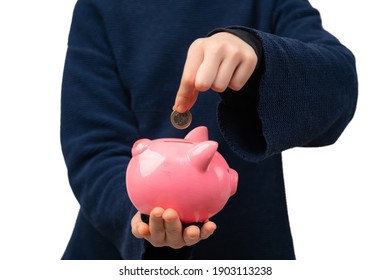 Close Up Of Young Entrepreneur Inserting Coin Into Piggy Bank. Financial Education For Kids.