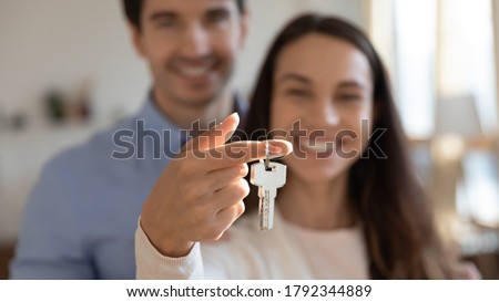 Close up young excited couple showing keys in hands to camera. Happy homeowners celebrating moving in new apartment or last banking mortgage payment, feeling glad of purchasing property, real estate.