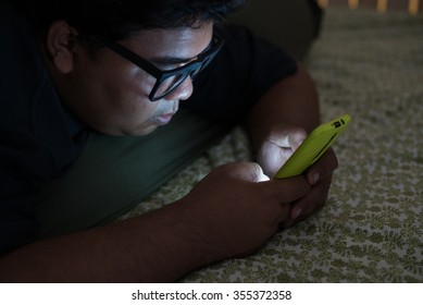 Close Up Young Fat Man  Texting On Mobile Phone At Night In Dark Room.