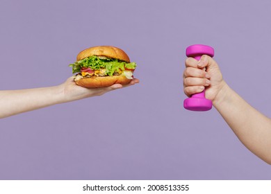 Close Up Young Female Arm Hand Hold Violet Dumbbells Vs And Junk Fast Food Hamburger Cheeseburger Burger Isolated On Purple Color Background Home Gym Unhealthy Nutrition Diet Sport Motivation Concept