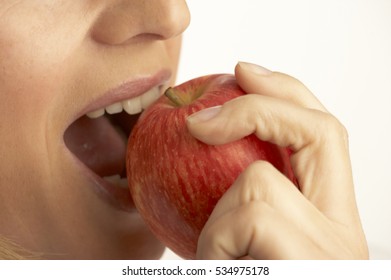 CLOSE UP OF YOUNG FEMALE EATING FRESH RED APPLE