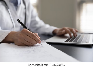 Close Up Young Female Gp Family Doctor Therapist Handwriting Notes In Paper Documents, Making Prescription To Patient, Giving Distant Healthcare Consultation Working On Computer In Clinic Office.
