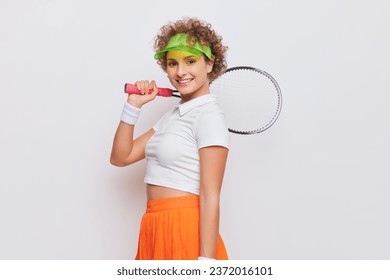 Close up of young female tennis player posing half turned with tennis racket on her shoulder, active life concept, copy space - Powered by Shutterstock