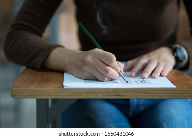 Close up of young female university student concentrate doing  examination in classroom. Girl student writes the exercise of the examinations in the classroom.
