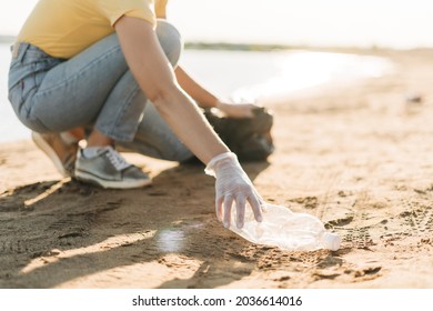 Close Up Young Female Volunteer Hand Picking Up Trash, A Plastic Bottles And Coffee Cups, Clean Up Beach With A Sea. Woman Collecting Garbage. Environmental Ecology Pollution Concept. Earth Day.