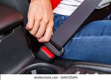 Close up young female in white t-shirt and jeans fastens or unfastens car seat belt with her hand in modern car. Safety and transport concept - Powered by Shutterstock