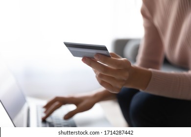 Close up young focus on plastic credit debit card in female hands, Young woman enjoying shopping online on computer, purchasing goods, ordering products food delivery or booking flight tickets hotel. - Shutterstock ID 1714287442
