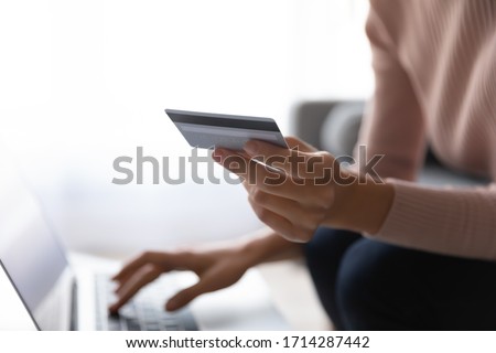Close up young focus on plastic credit debit card in female hands, Young woman enjoying shopping online on computer, purchasing goods, ordering products food delivery or booking flight tickets hotel.