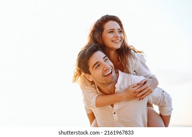 Close up young fun happy enamored smiling couple two friends family man woman in casual clothes boyfriend give piggyback ride to joyful, girlfriend sit on back look aside on light white sky background - Powered by Shutterstock