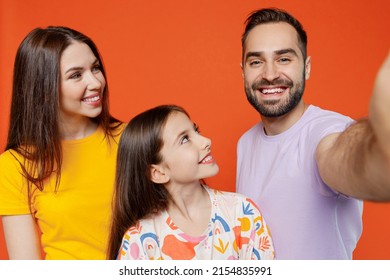 Close up young fun happy parents mom dad with child kid daughter teen girl in basic t-shirts do selfie shot pov on mobile phone isolated on yellow background. Family day parenthood childhood concept.