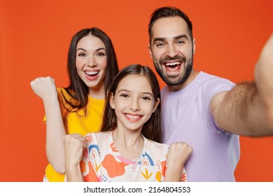 Close Up Young Fun Parents Mom Dad With Child Kid Daughter Teen Girl In Basic T-shirts Doing Selfie Shot Pov Mobile Phone Do Winner Gesture Isolated On Yellow Background. Family Day Parenthood Concept