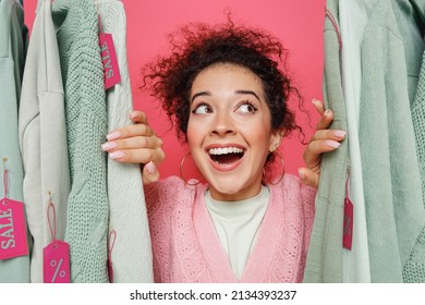 Close Up Young Fun Smiling Minded Happy Caucasian Female Costumer Woman 20s Wearing Sweater Stand Near Clothes Rack With Tag Sale In Store Showroom Isolated On Plain Pink Background Studio Portrait
