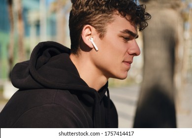 Close Up Young Handsome Man Listening Music In Wireless Earphones. Attractive Guy Resting After Workout Outdoor