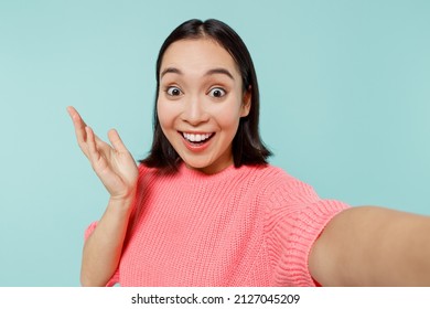 Close Up Young Happy Fun Woman Of Asian Ethnicity 20s In Pink Sweater Do Selfie Shot Pov On Mobile Phone Spread Hands Isolated On Pastel Plain Light Blue Background Studio. People Lifestyle Concept