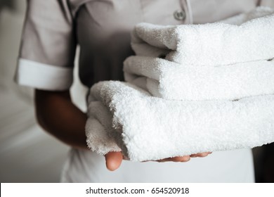 Close up of a young hotel maid holding clean folded towels
