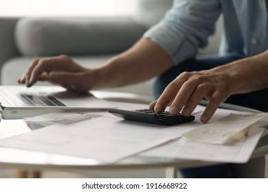 Close up of young male accountant hands make audit of expenses calculate charges based on paper documents. Cropped shot of man bookkeeper work with bills pay fees taxes online using web app on laptop - Powered by Shutterstock