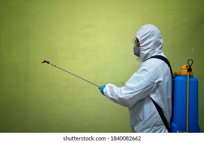 Up close a Young male contractor disinfecting in coronavirus concept over green background and selective focus. 

 - Shutterstock ID 1840082662