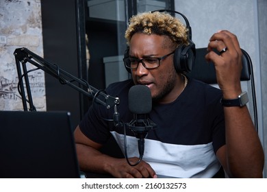 A Close Up Of A Young Male Radio Host, Who Looks Focused, Speaks Into The Microphone With His Hand Raised. The Host Of The Online Broadcast Tells Listeners A Real Story From Life