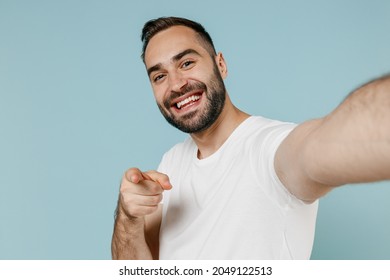 Close Up Young Man 20s Wearing Casual Basic White T-shirt Doing Selfie Shot Pov On Mobile Phone Point Index Finger Camera On You Isolated On Plain Pastel Light Blue Color Background Studio Portrait.