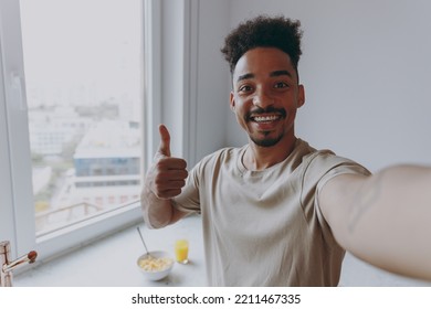 Close Up Young Man Of African American Ethnicity Wear Casual Clothes Show Thumb Up Doing Selfie Shot Pov On Mobile Phone Prepare Cooking Food In Light Kitchen At Home Alone Indoor Healthy Diet Concept