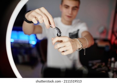 Close Up Of Young Man Demonstrating Beauty Massager While Filming Male Skincare Tutorial With Ring Light, Copy Space