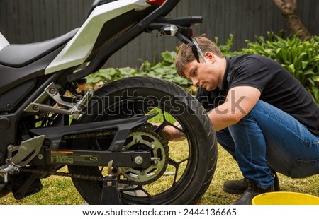 Close up of young man doing back yard motorcycle maintenance.