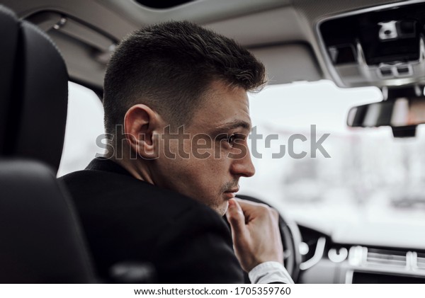 Close up of young man driving in car while\
renting it. Rent and trade-in\
concept
