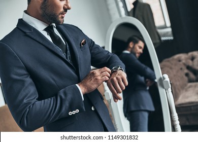 Am I Late? Close Up Of Young Man In Full Suit Checking The Time While Standing In Front Of The Mirror Indoors        