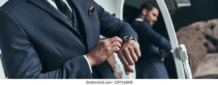 Am I Late? Close Up Of Young Man In Full Suit Checking The Time While Standing In Front Of The Mirror Indoors