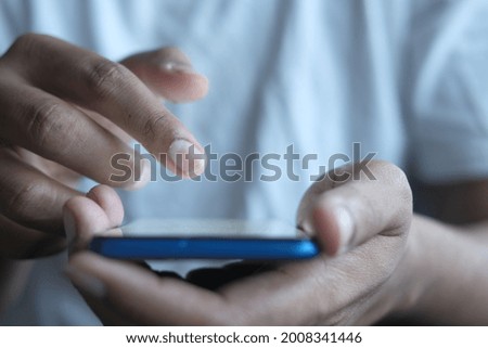 Close up of young man hand using smart phone.