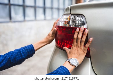Close up young man hands auto mechanic checking tail light, Automobile servicing and repair concept.