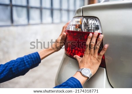 Close up young man hands auto mechanic checking tail light, Automobile servicing and repair concept.