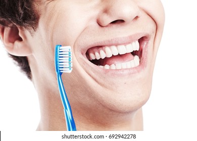 Close Up Of Young Man Holding Toothbrush Near His Toothy Smile With Perfect Healthy White Teeth Isolated On White Background - Dental Care Concept