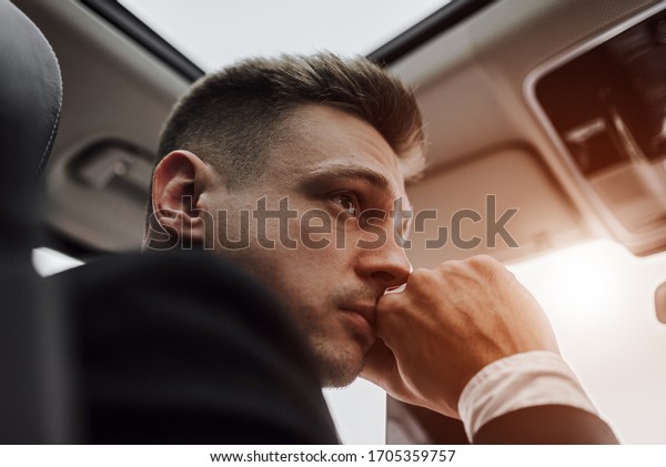 Close up of young man looking away while\
sitting on seat of car. Rent and trade-in\
concept